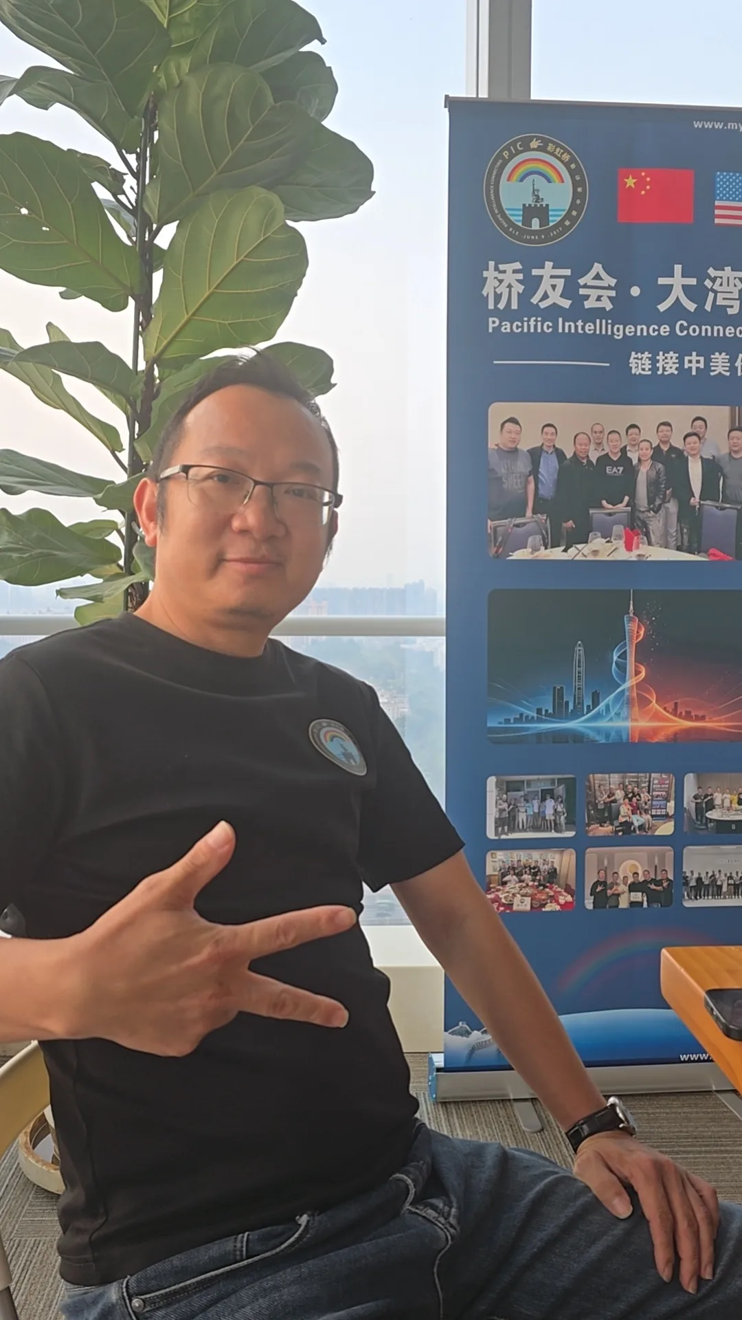 彩虹桥 9/5 广州番禺桥友会:一位桥友在会议室的易拉宝旁留影